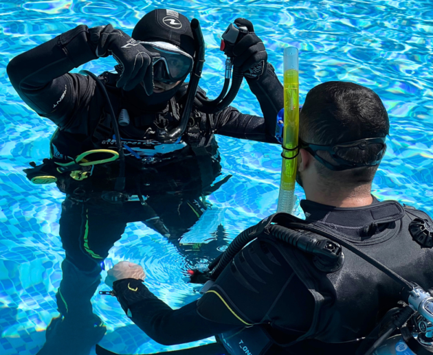 Scuba instructor explains a student on how to move underwater using their legs during a dive