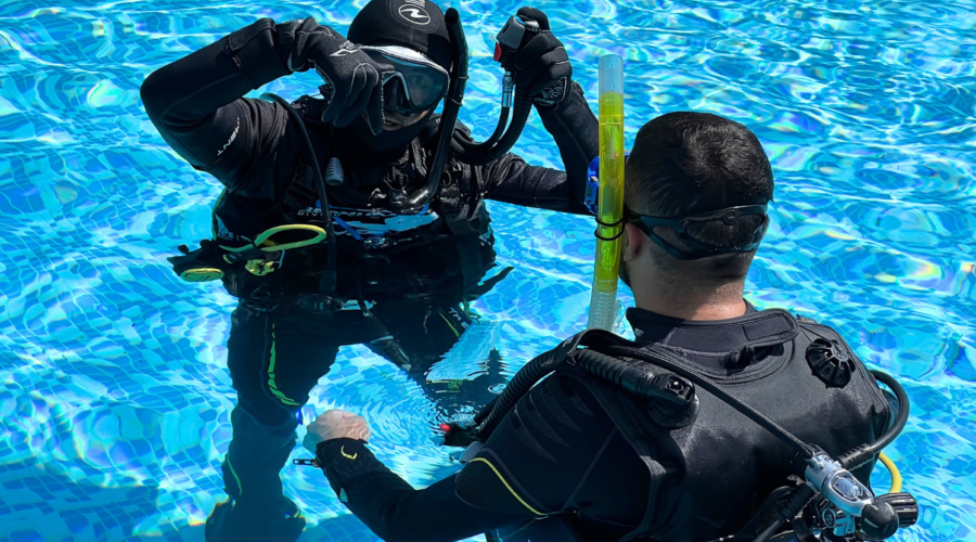 Scuba instructor explains a student on how to move underwater using their legs during a dive
